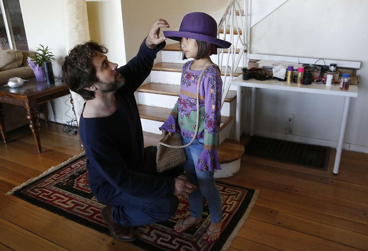 Jonathan Kos-Read helps one of his daughters Roxanne, 9, with a hat choice before the family heads to the zoo from their home April 16, 2016 in Oakland, Calif. Kos-Read moved his family to the East Bay after having lived in China for years.