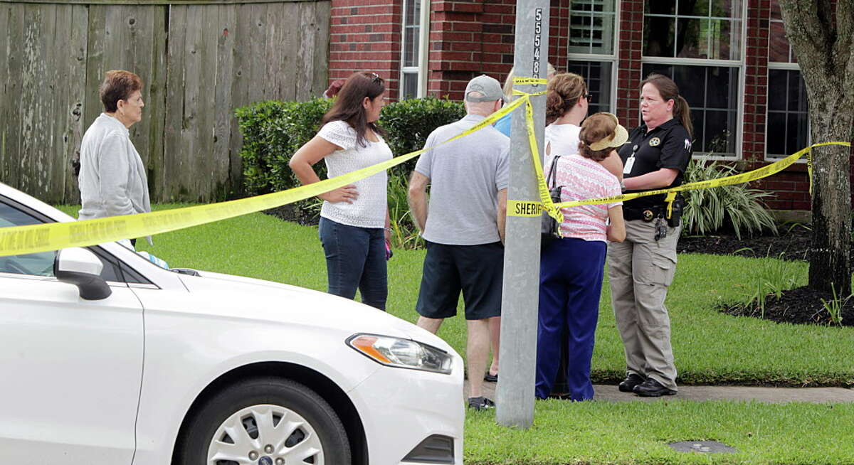 A Fort Bend County Sheriff Deputy speaks with neighbors as officers investigate a murder suicide involving 2 adults and two children at a home in the 1300 block of Longdraw Tuesday, April 19, 2016, in Katy.