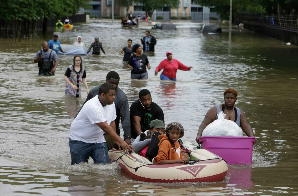 Residents of the Arbor Court Apartments help some of their neighbors to safety as they were forced to evacuate their flooded complex in the Greenspoint area on Monday. (Melissa Phillip/Houston Chronicle)