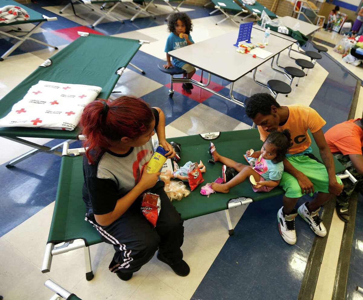 Alma Amado feeds her daughter, Catalia Sampson, 2, on Tuesday with boyfriend Demetric Sampson in a Red Cross shelter at Brookshire's high school. More than 430 people spent Monday night at 12 Red Cross shelters across the region. ﻿