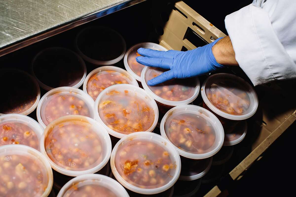 A worker places a container of oliver chickpea stew into a bin at the Munchery kitchen in San Francisco, Calif. on Tuesday, April 19, 2016.