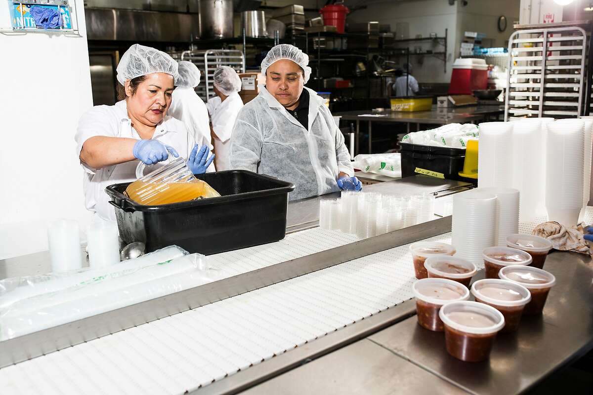 Reyna Sigoran, left, transfers sauce into a container at the plating station at the Munchery kitchen in San Francisco, Calif. on Tuesday, April 19, 2016.