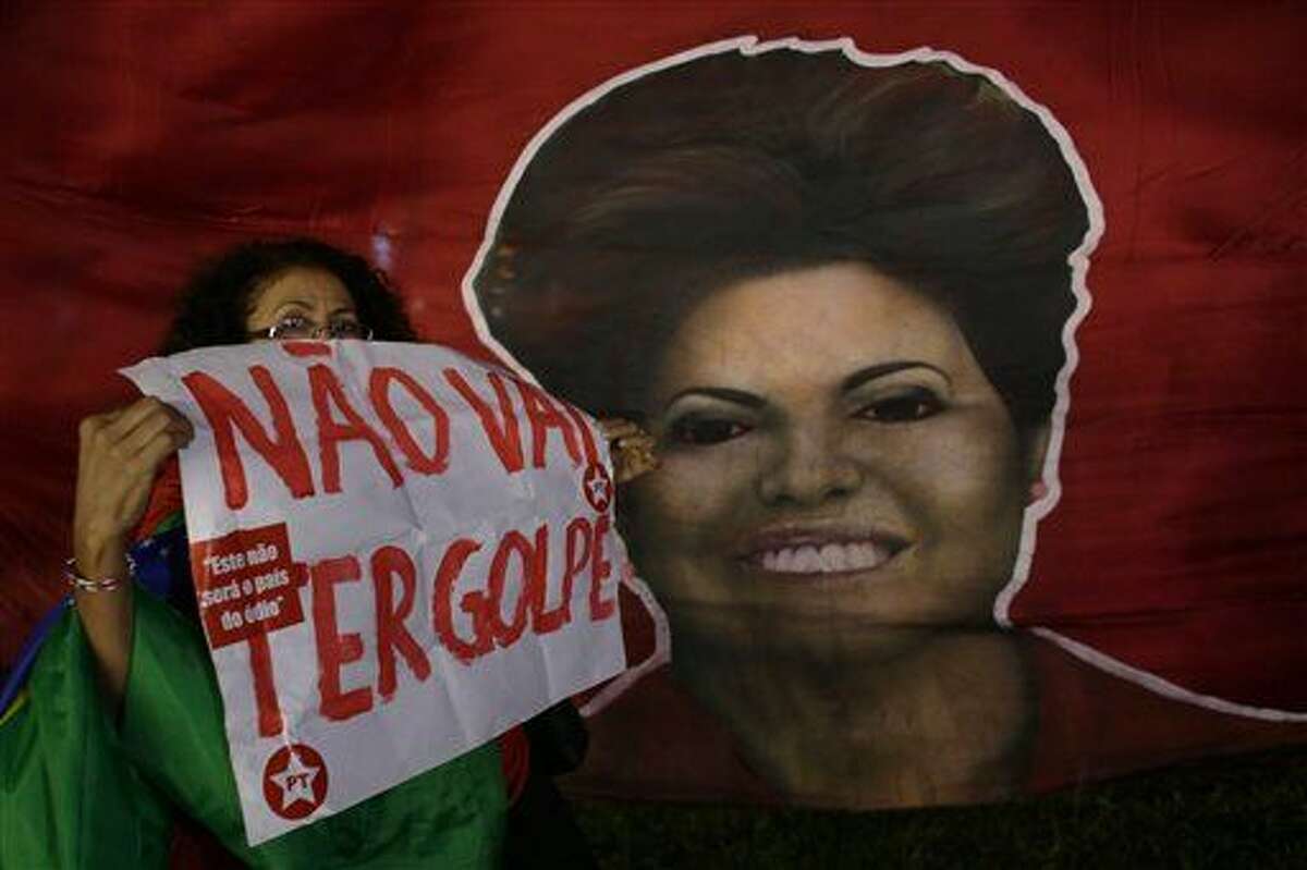 Una mujer muestra un cartel junto a una fotografía de la presidenta de Brasil, Dilma Rousseff, durante una manifestación para apoyarla a ella y al expresidente Luiz Inacio Lula da Silva, en Brasilia, Brasil, el viernes 18 de marzo de 2016. El cartel tiene la leyenda en portugués: "No habrá golpe". (Foto AP/Eraldo Peres)