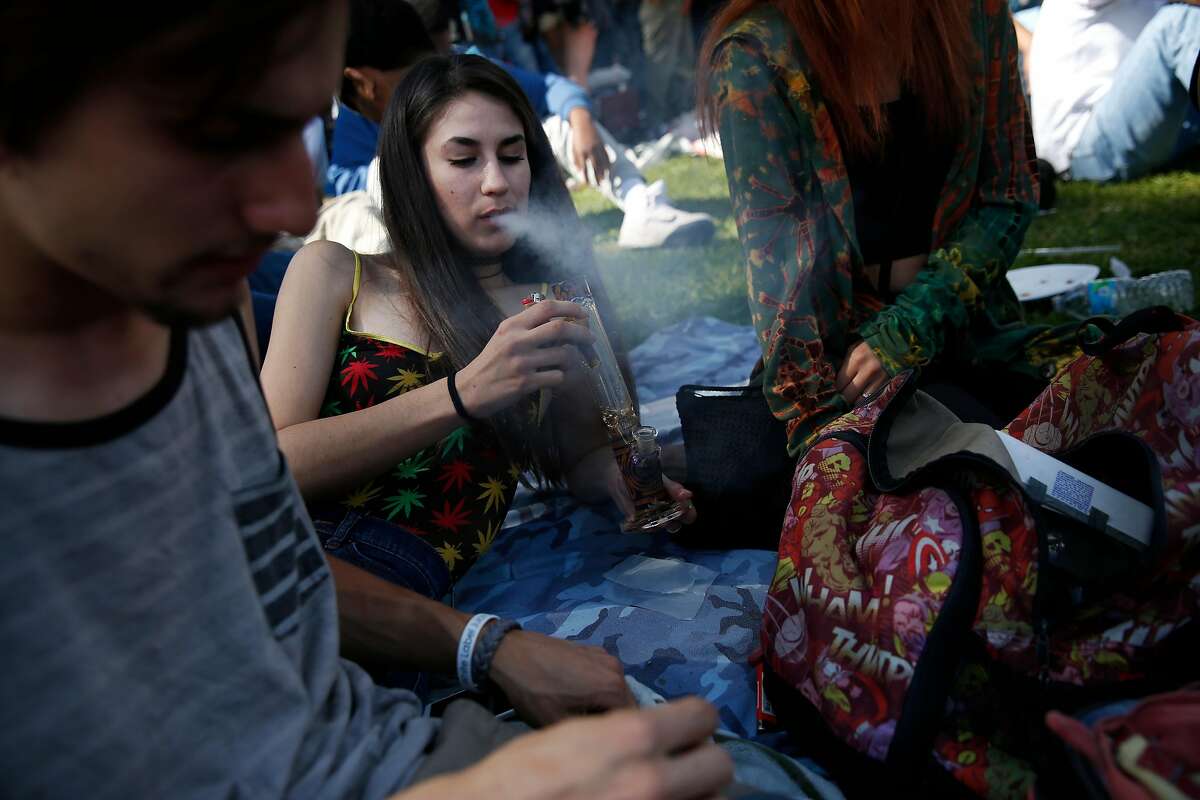 Kaylie Gonzales, center, exhales smoke from a bong hit while friends Ryan Wilson, left, and sister Lenay Gonzales, right, hang out nearby during the annual 4/20 celebration in Golden Gate Park's Sharon Meadow and Hippie Hill April 20, 2016 in San Francisco, Calif.