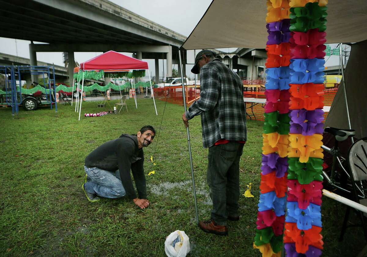 Danny Garcia (left) and Ricardo Garza, his uncle, set up tents in the rain along the Fiesta parade route on Broadway under U.S. 281.