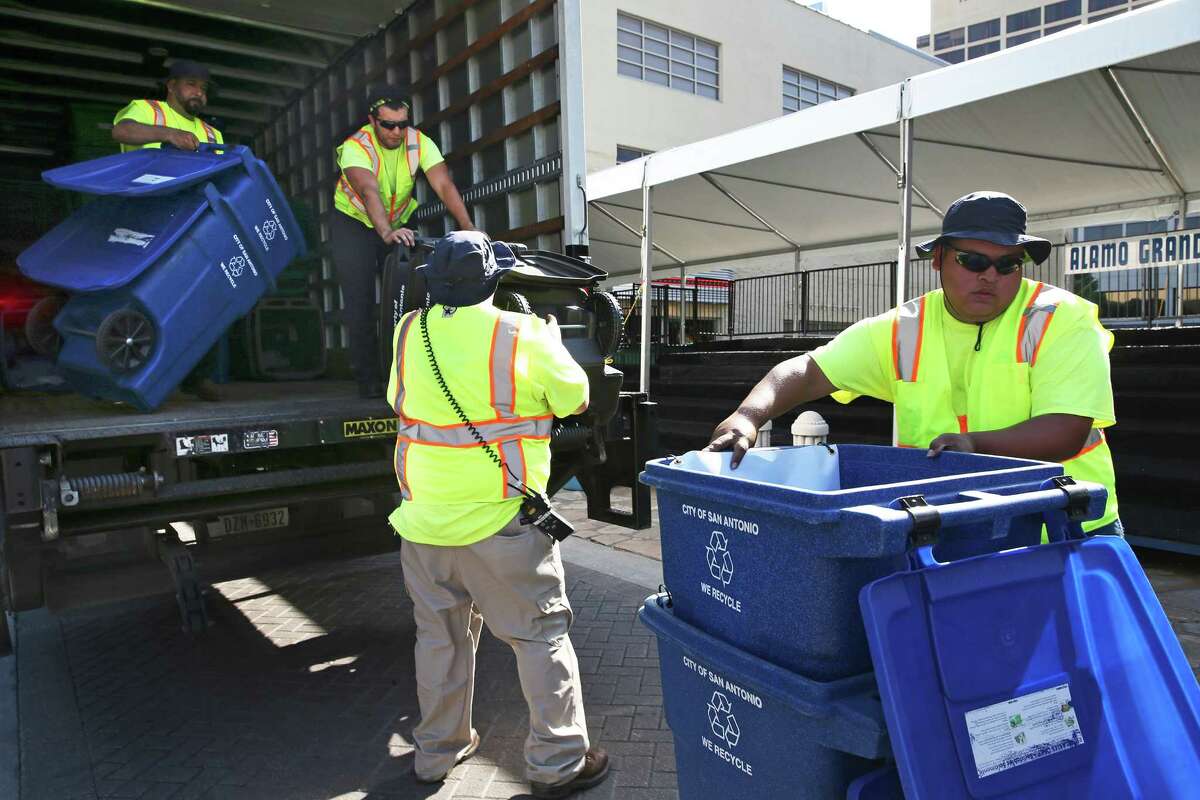 Solid waste workers place recycling containers and waste bins in Alamo Plaza as they make their way along the downtown parade route on April 21, 2016.