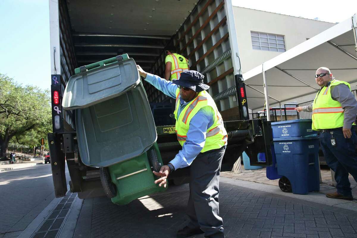 Solid waste workers place recycling containers and waste bins in Alamo Plaza as they make their way along the downtown parade route on April 21, 2016.