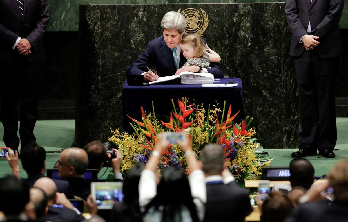 U.S. Secretary of State John Kerry holds his granddaughter Isabel Dobbs-Higginson as he signs the Paris Agreement on climate change, Friday, April 22, 2016 at U.N. headquarters. (AP Photo/Mark Lennihan)