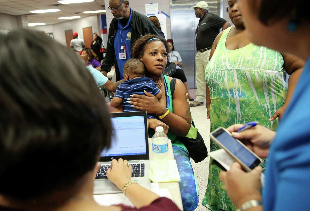 Dana Watson talks to Red Cross and city officials about getting a voucher as she holds her six-month-old son, Isaiah at the M.O. Campbell shelter on Friday, April 22, 2016, in Houston.