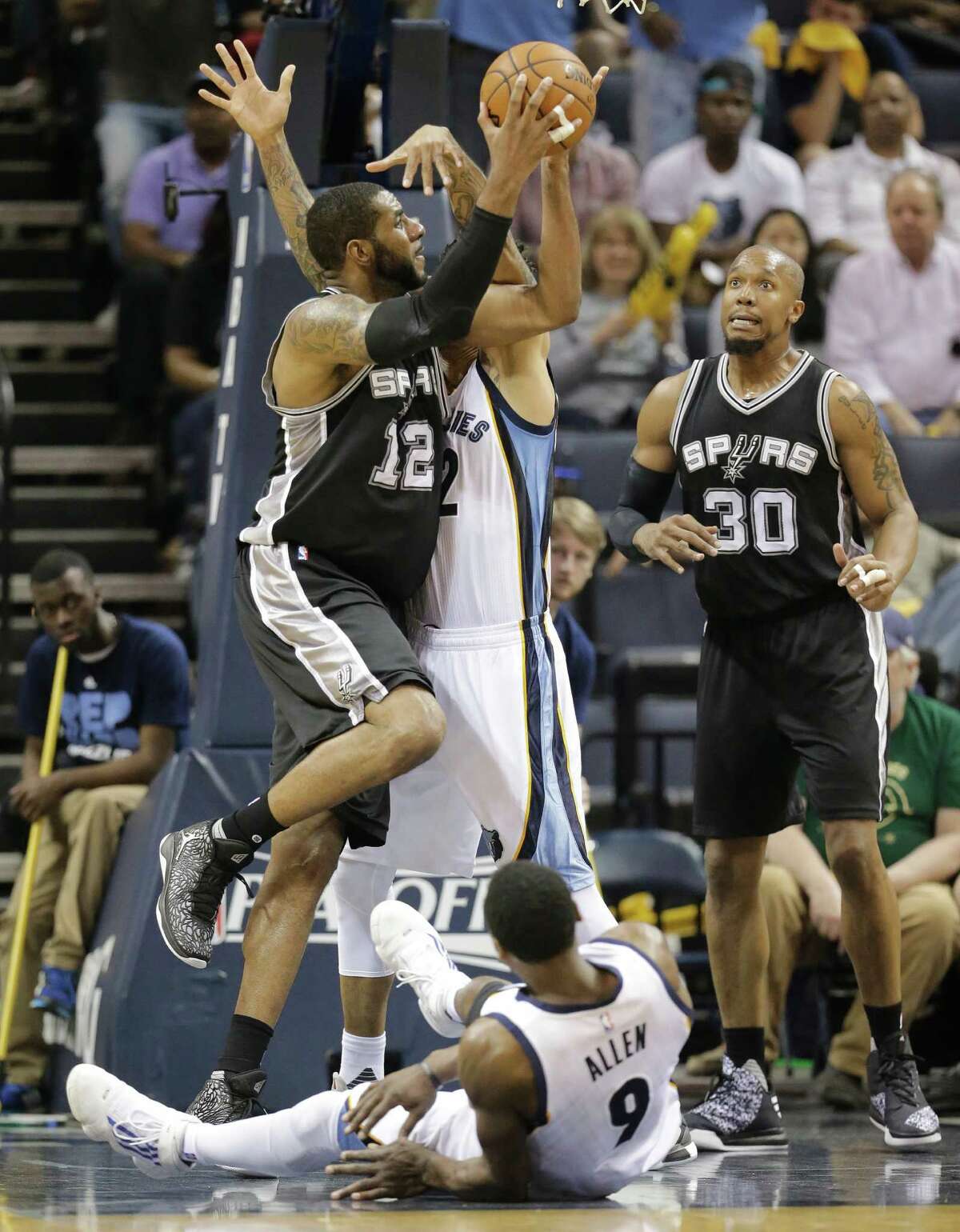 San Antonio Spurs forward LaMarcus Aldridge (12) shoots between Memphis Grizzlies forward Matt Barnes (22) and Tony Allen (9) during the first half of Game 3 in a first-round NBA basketball playoff series Friday, April 22, 2016, in Memphis, Tenn. Spurs forward David West (30) watches the play. (AP Photo/Mark Humphrey)