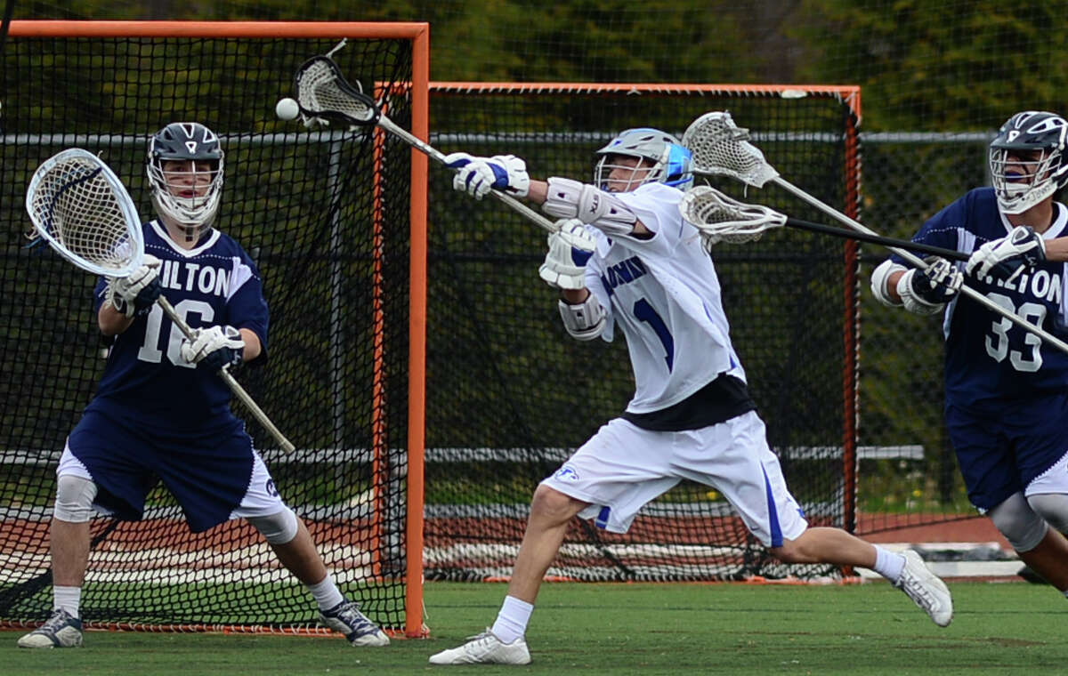 Darien’s Brian Minicus (#1) takes a shot on Wilton goalie Andrew Calbrese as Wilton’s Tyler Previte (#33) defends during their game on Saturday at Darien High School.
