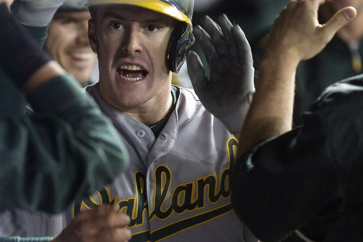 Oakland Athletics' Mark Canha celebrates in the dugout after hitting a solo home run during the first inning of a baseball game against the Toronto Blue Jays in Toronto on Saturday, April 23, 2016. (Chris Young/The Canadian Press via AP) MANDATORY CREDIT