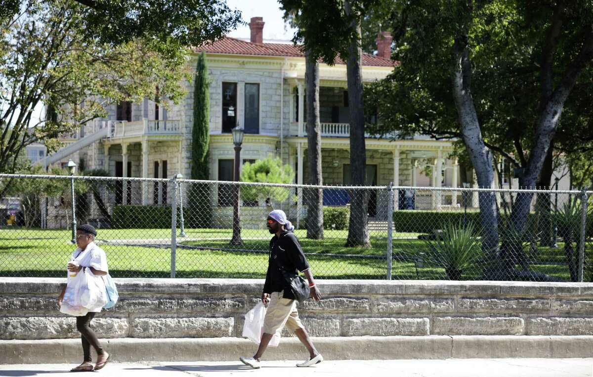 Pedestrians walk along the historic wall on Flores Street in front of the Commander's House on H-E-B's headquarter property between Cesar Chavez and Arsenal in 2013.