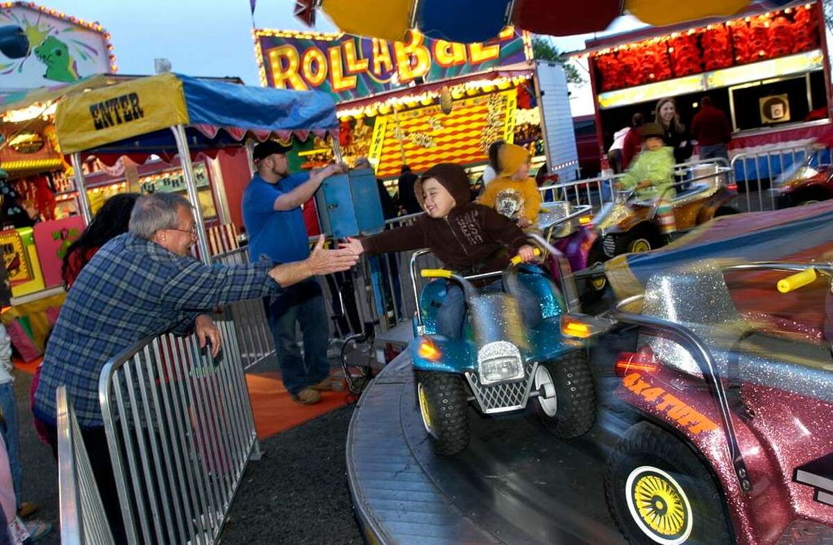 James Ligouri, left, of Fairfield, puts his hand out to "high five" his nephew Alex Kanlong, 3, on one of the kiddie rides during the opening day of the annual McKinley School Carnival at Jennings Beach in Fairfield, Conn. on Thursday April 15, 2010.