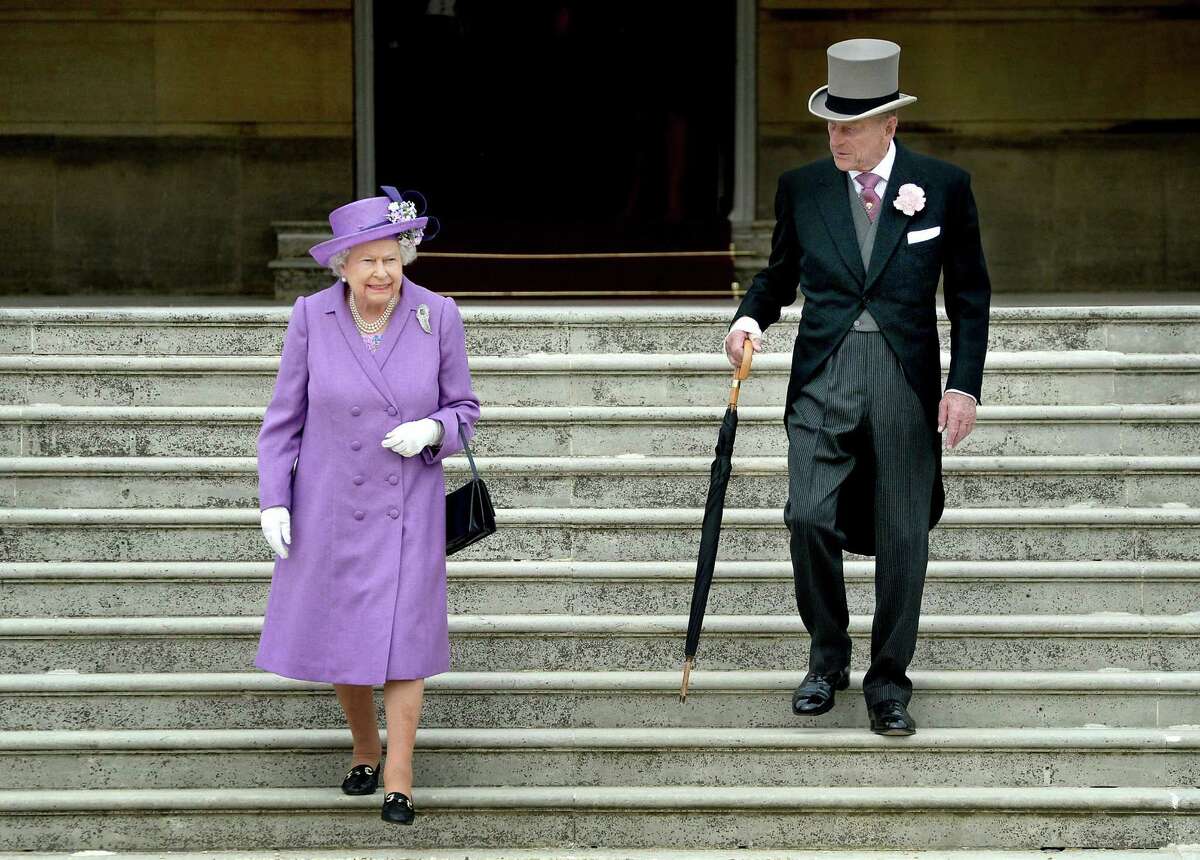 Britain's Queen ELizabeth II, shown here in 2014, carries her black handbag nearly everywhere in public. She even signals her staff with how she positions it.