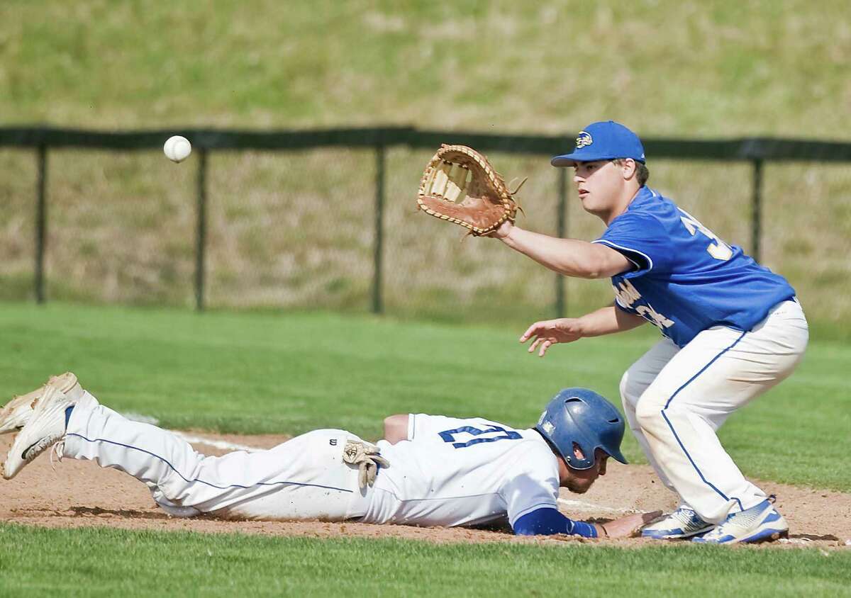 Newtown High School's Dylan Tyrrell dives back to first as Brookfield High School's Austin Reich takes the pick-off throw in a game played at the Newtown Youth Academy. Monday, April 25, 2016