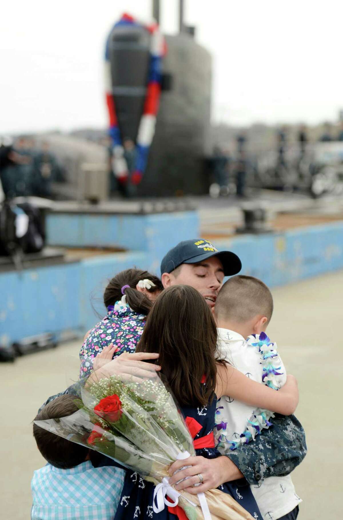 Petty Officer 2nd Class Clint Van de Water hugs his children Elizabeth, 10, Luke, 7, Isabelle, 7, and Jaxon 3, as the U.S. Navy submarine USS Toledo (SSN 769) returns to the Navy Submarine Base in Groton, Conn., Monday, April 25, 2016, following a six-month deployment. The Toledo visited ports in Bahrain, France, Spain and Greece.