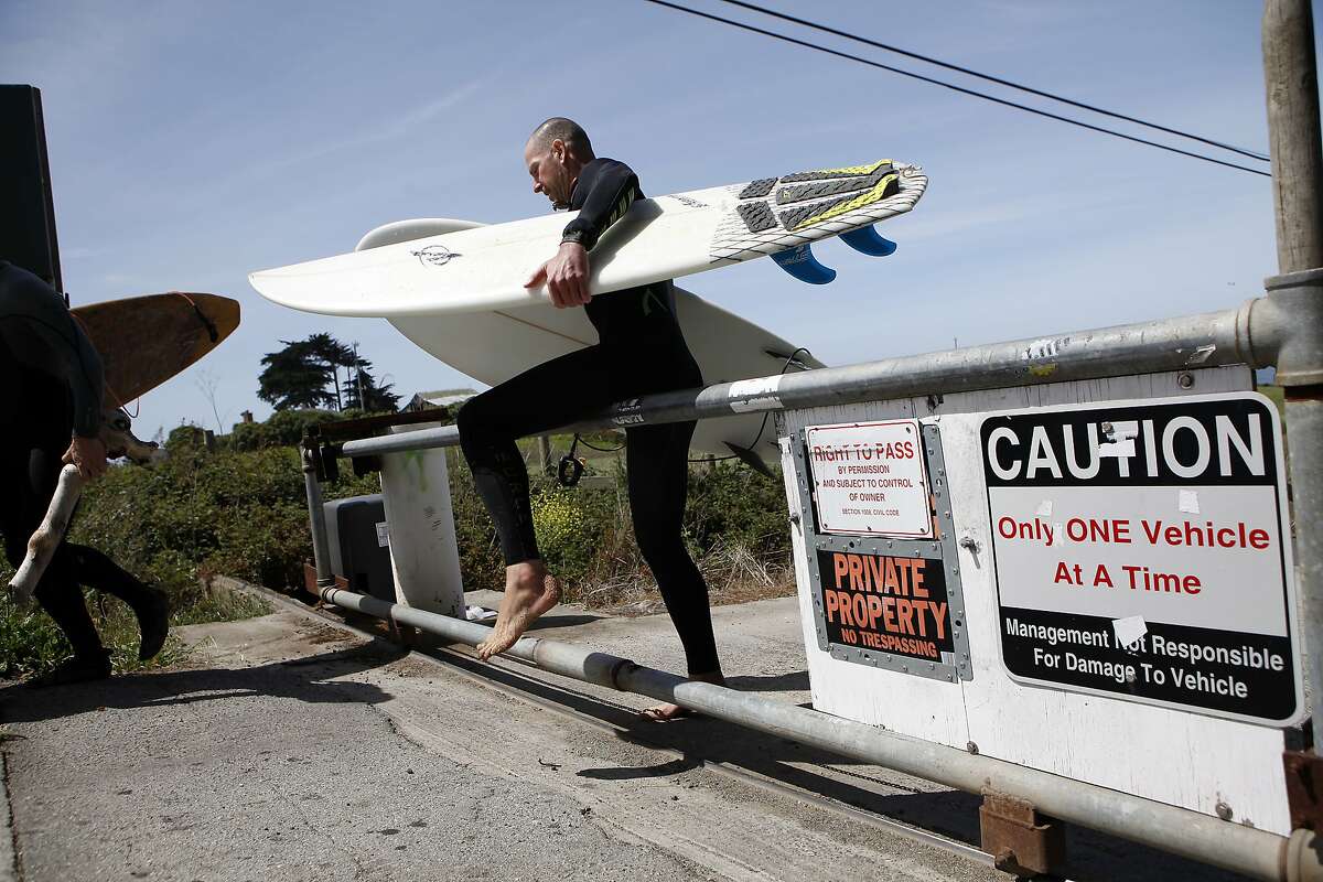 After a surf session, Morgan Williams of San Francisco climbs over a locked gate that blocks the only public access to Martin's Beach in Half Moon Bay, CA, Thursday May 15, 2014.