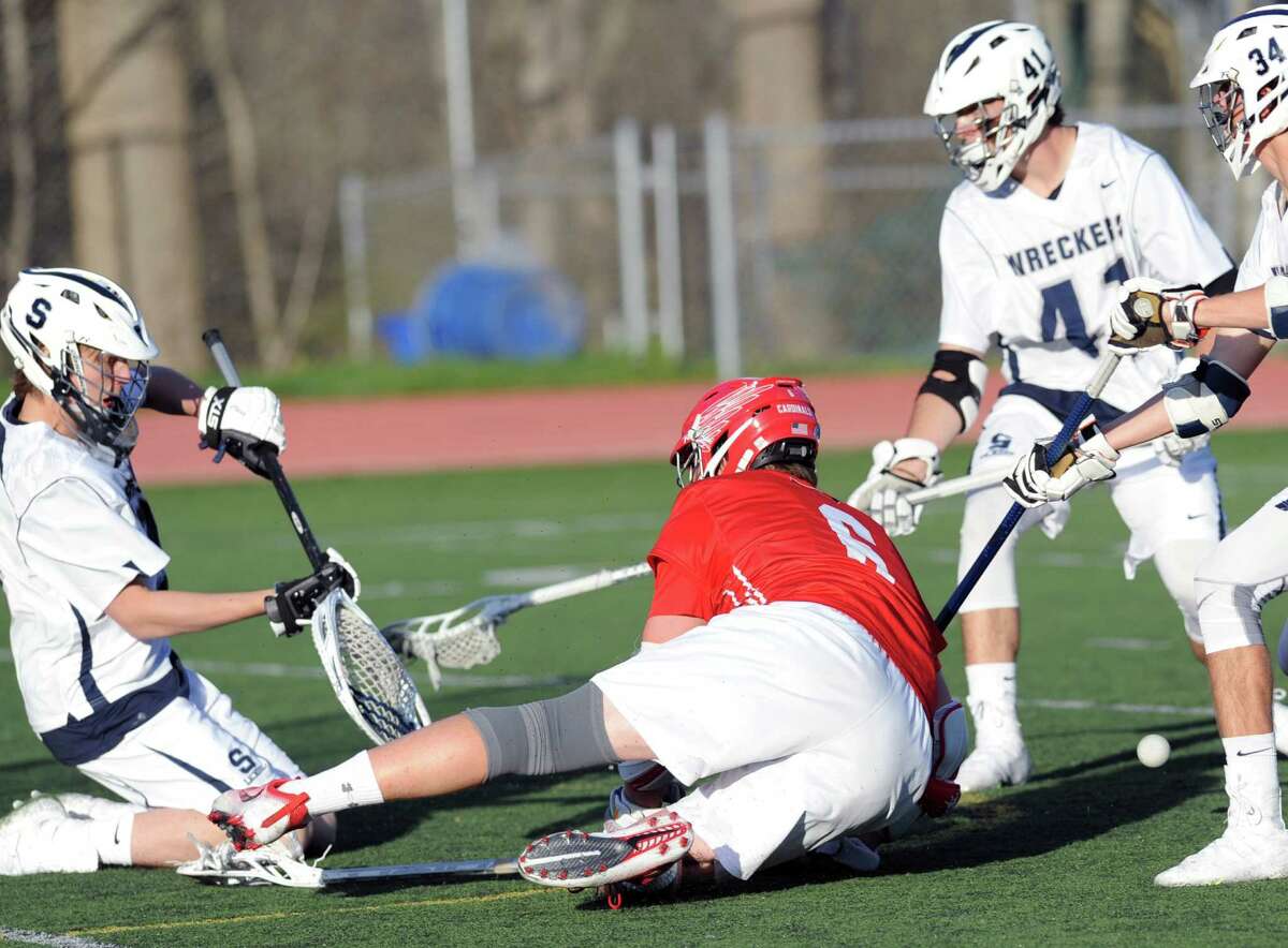 Staples goalie Peter Burger, left, stops a point-blank shot by Scott Harrington (#6) of Greenwich, center, during the boys high school lacrosse match between Staples High School and Greenwich High School at Staples in Westport, Conn., Tuesday, April 19, 2016. In background at right is Drew O'Brien (#41) of Staples.