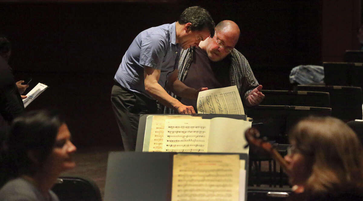 Guest conductor Jacques Lacombe (left) looks over material with bass clarinetist Rodney Wollan. The symphony’s finances have been a longtime source of worry for its outside donors.