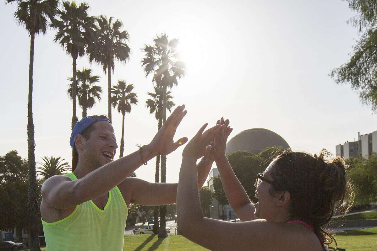 Peteris Liepins, left, high fives Angela Velez at Dolores Park after a workout on Friday, April 29, 2016 in San Francisco, Calif. Prop B would provide $3 million a year for parks from the city's general fund.