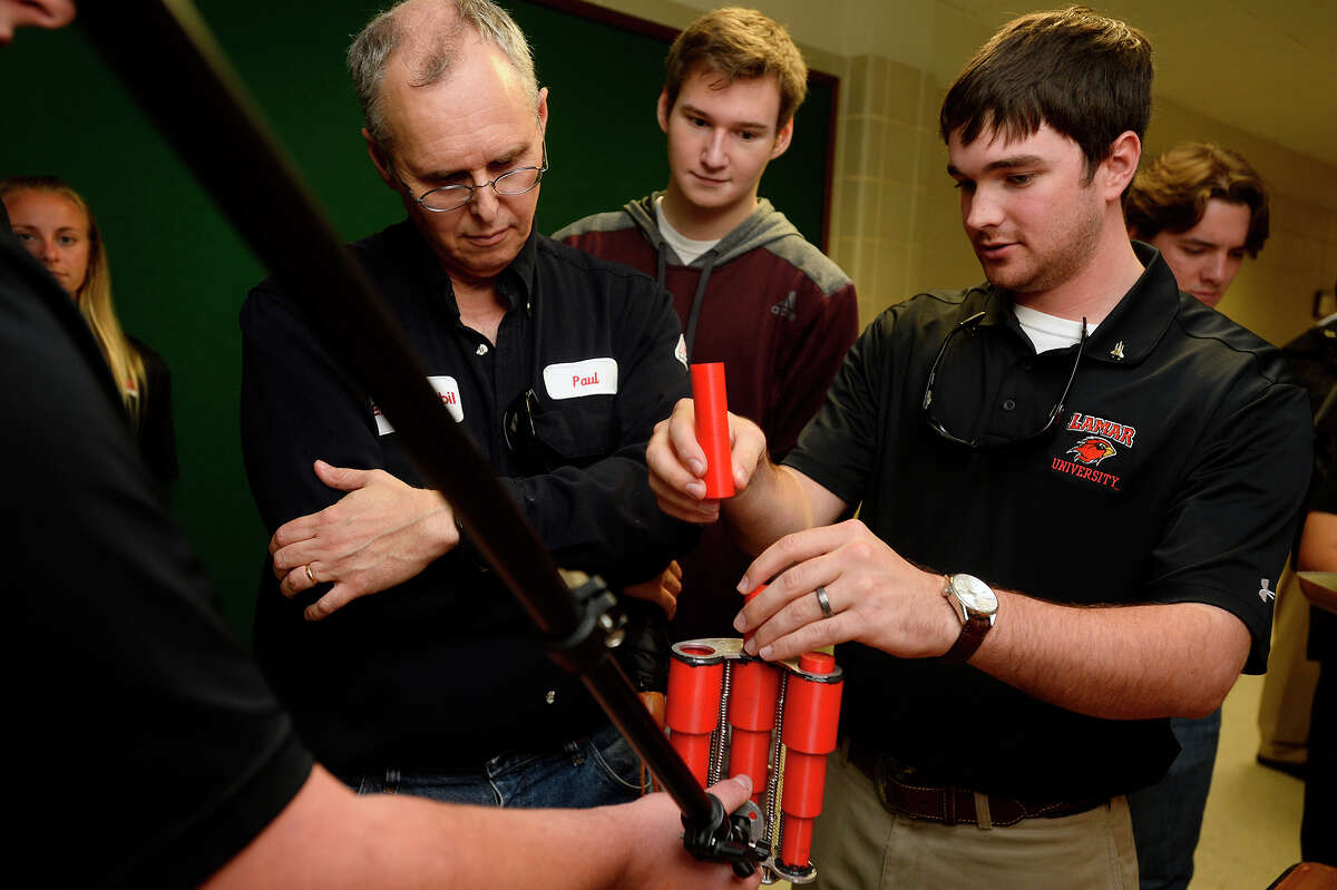 Paul Hall, lead process engineer with ExxonMobil, watches as Matthew Perdue, right, and his teammates demonstrate their Mars rover design system during the senior design symposium for Lamar University engineering students on Friday. The students designed a system to remove soil and rock core samples from the drill and move them to be analyzed. Photo taken Friday 4/29/16 Ryan Pelham/The Enterprise