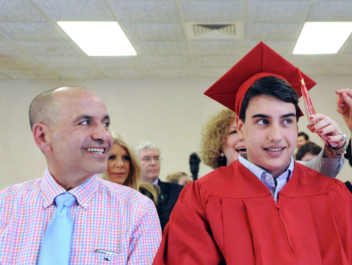 At left, Akram El-Tayyeb, smiles at his son, Ferris El-Tayyeb, 17, during a special graduation ceremony for Ferris at Greenwich High School, Conn., Friday, April 29, 2016. The special ceremony was arranged so that Ferris' father, Akram El-Tayyeb, who is terminally ill with cancer and might not make it until the June commencement, could see his son graduate from high school.