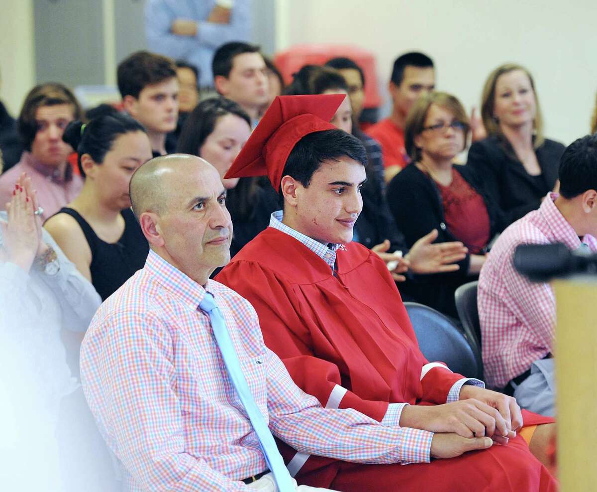At left, Akram El-Tayyeb, holds the hand of his son, Ferris El-Tayyeb, 17, right, during a special graduation ceremony for Ferris at Greenwich High School, Conn., Friday, April 29, 2016. The special ceremony was arranged so that Ferris' father, Akram El-Tayyeb, who is terminally ill with cancer and might not make it until the June commencement, could see his son graduate from high school.