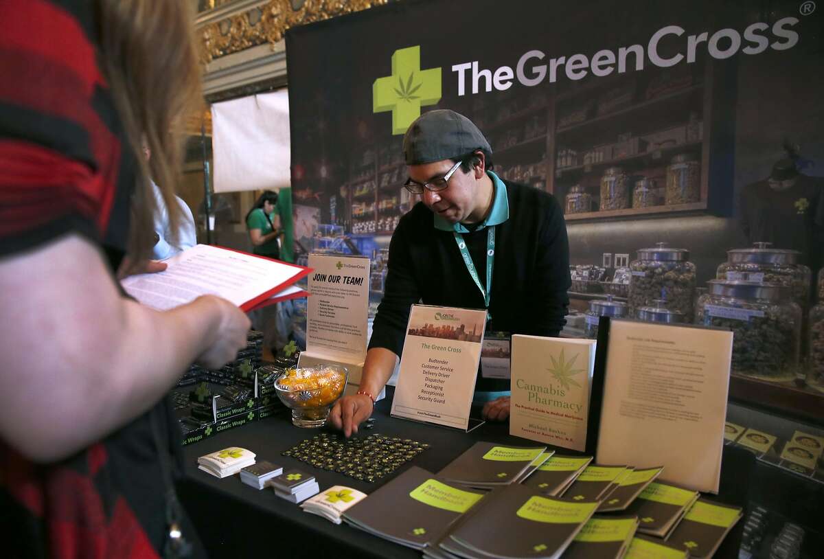 Michael Yannacone organizes his display for The Green Cross before Taylor Collins submits her resume at a cannabis industry job fair in San Francisco, Calif. on Saturday, April 30, 2016.