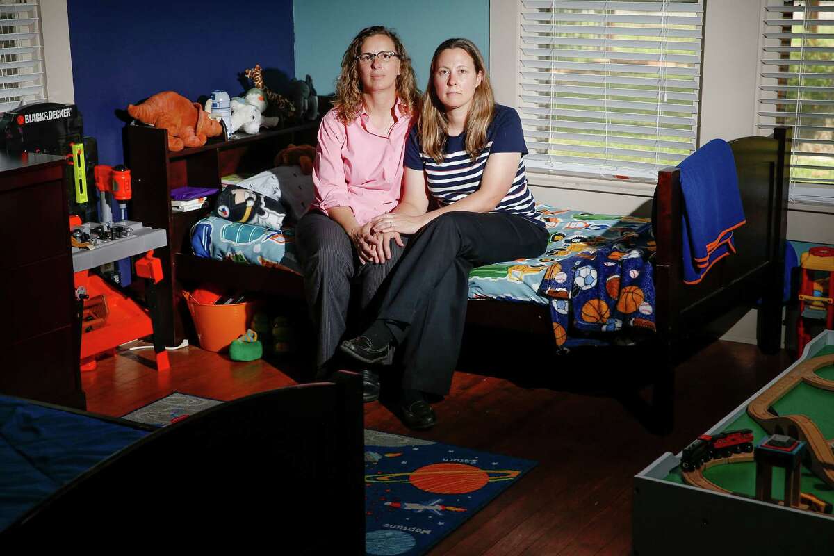 Foster parents Angela Sugarek, left, and Carol Jeffery sit Wednesday on the empty bed of the younger of their two foster children. ﻿