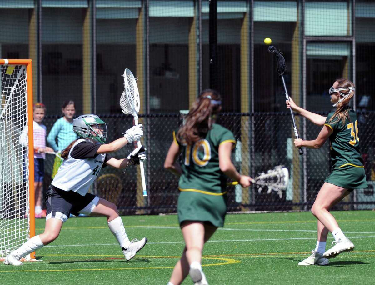 At right, Olivia Koorbusch of Greenwich Academy scores a second half goal getting her shot past Sacred Heart goalie Maddie McLane, right, as Koorbusch's teammate Anna Khoury (#10) looks on during the girls high school lacrosse match between Greenwich Academy and Sacred Heart School at Greenwich Academy, Saturday, April 30, 2016. Greenwich Academy won the match by a score of 12-9.