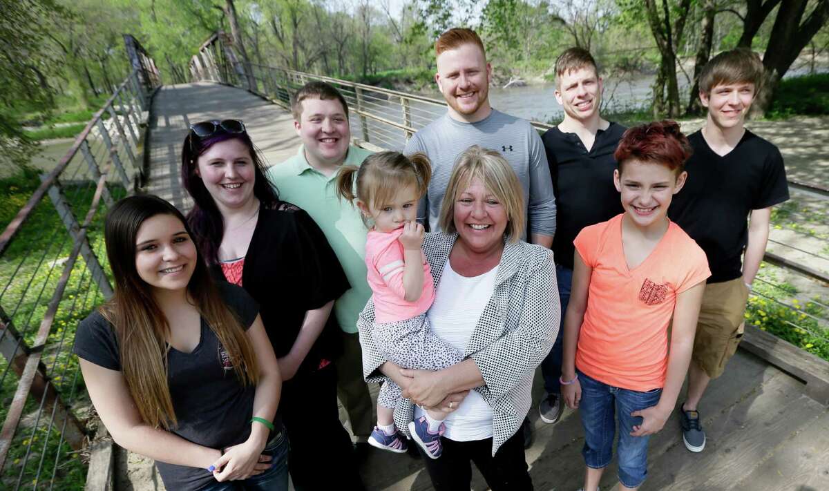 In this Tuesday, April 26, 2016 photo, Denise Moore, center, in white, of Des Moines, Iowa, poses with her family, from left, daughter Alex Gibbs, Emily Bosch, son Kodi Baughman, granddaughter MacKenzie Moore, sons Kori Moore, Kelli Moore, daughter Andy Gibbs, and son Kasi Baughman during a visit to Water Works Park, in Des Moines, Iowa. Moore, a mother of seven, nearly lost her parental rights after her arrest in 2003 for conspiracy to deliver methamphetamine. (AP Photo/Charlie Neibergall) ORG XMIT: IACN203