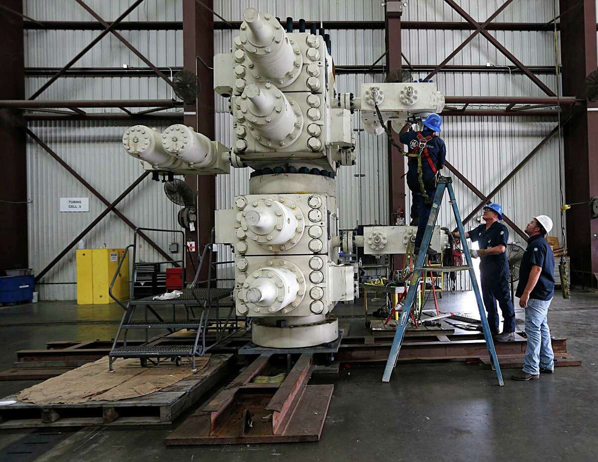 GE Oil & Gas employees work on a blowout preventer last week at GE's manufacturing facility. The firm is waiting to deploy the last blowout preventer it has because of the oil downturn.