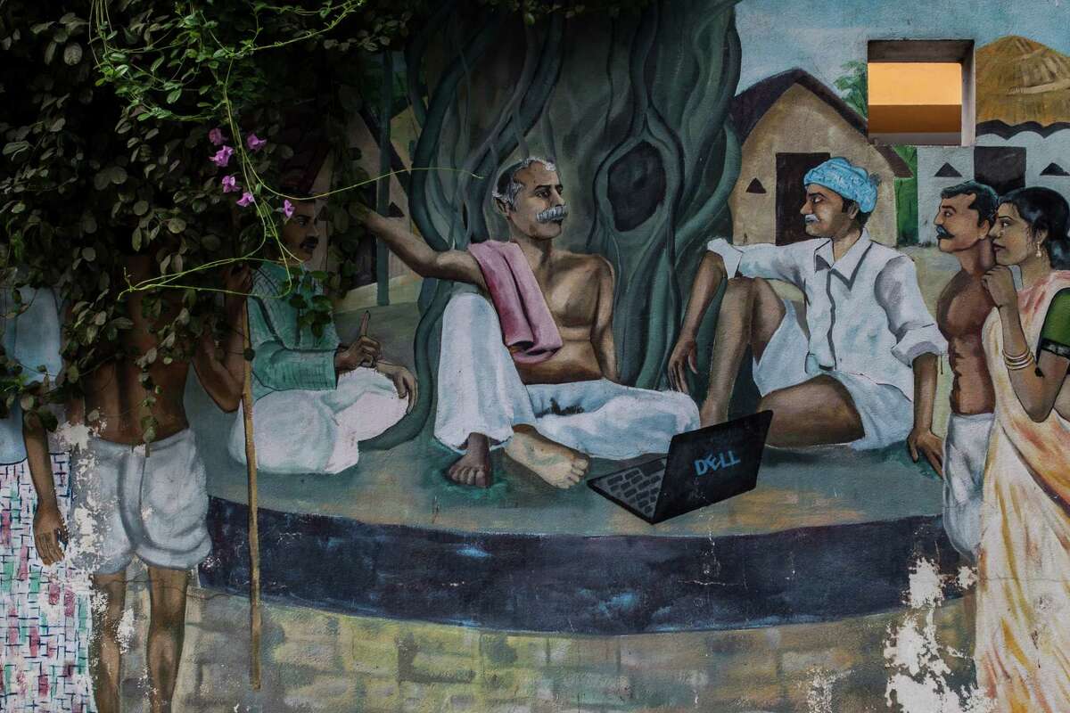 A mural depicting traditional Indian villagers using a laptop is painted on the fence of an engineering company in HITEC City in Hyderabad, India, where thousands of workers seek to obtain a guest worker visa to the U.S.