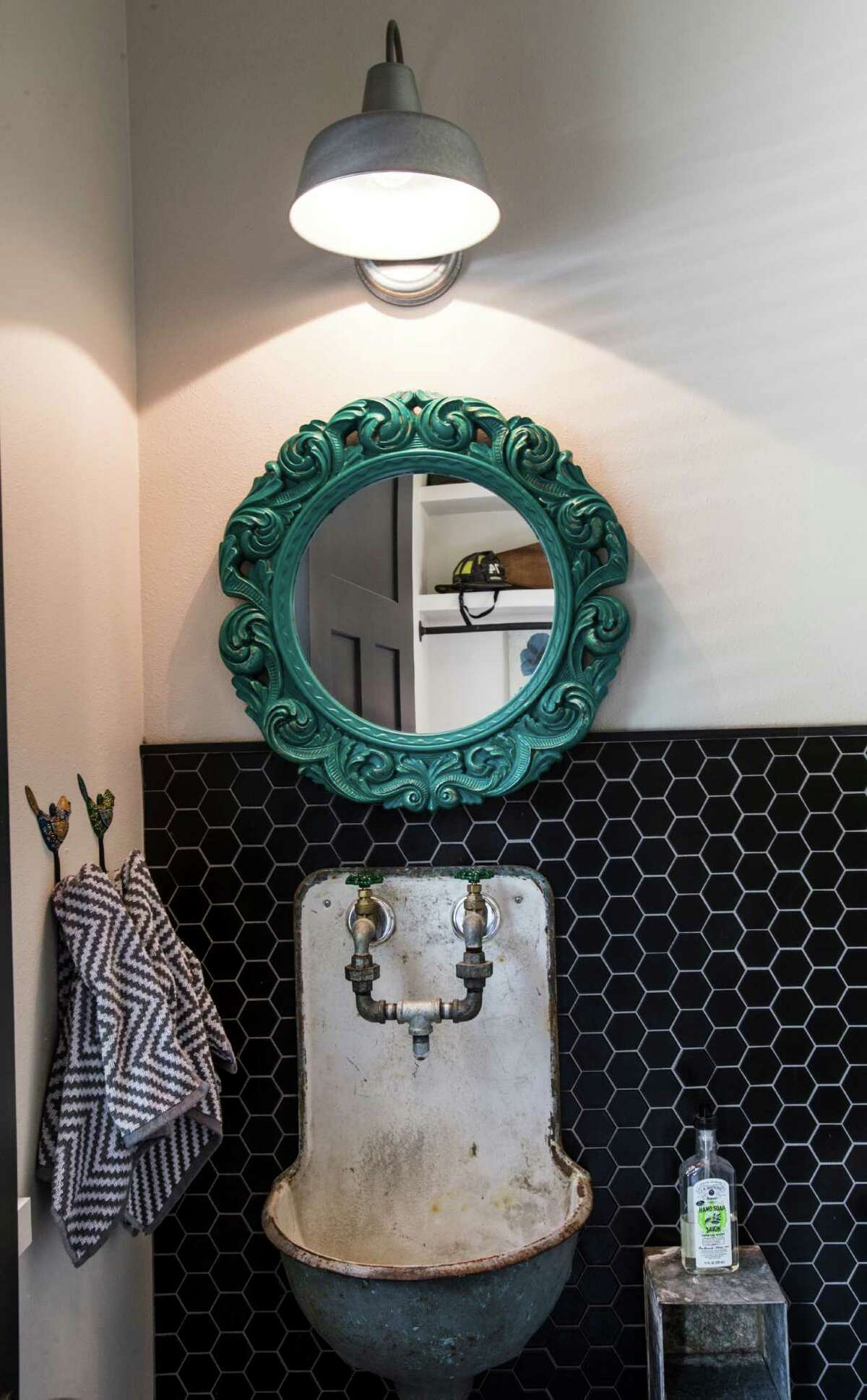 ﻿ANTIQUES:  An antique sink and mirror play off ﻿sleek black ﻿tiles in this powder room.