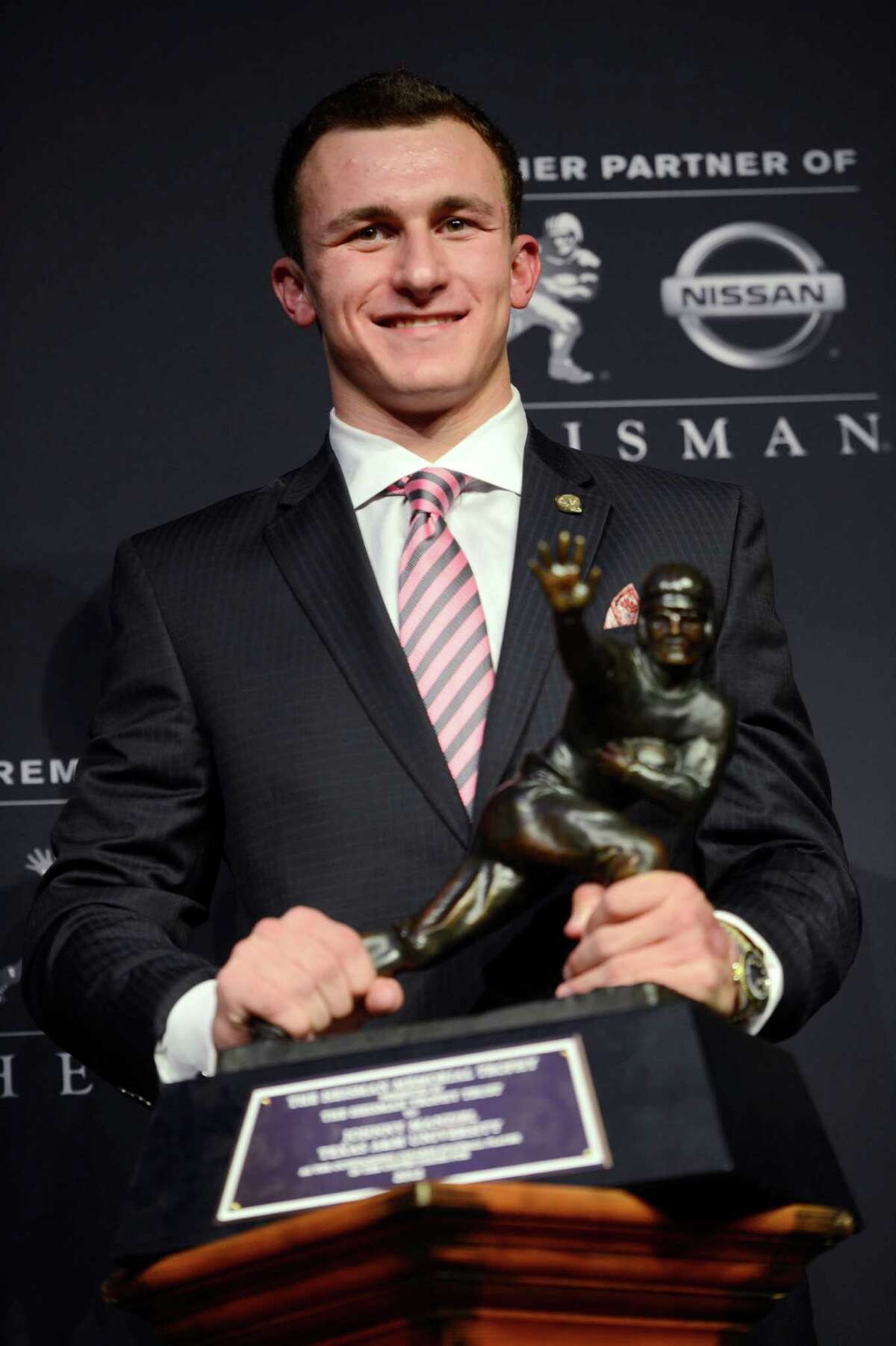 FILE - In this Dec. 8, 2012 file photo, then-Texas A&M quarterback Johnny Manziel poses with the Heisman Trophy after becoming the first freshman to win the college football award, in New York. Manziel was indicted by a grand jury on Tuesday, April 26, 2016, on misdemeanor charges stemming from a domestic violence complaint by his ex-girlfriend.(AP Photo/Henny Ray Abrams, File)