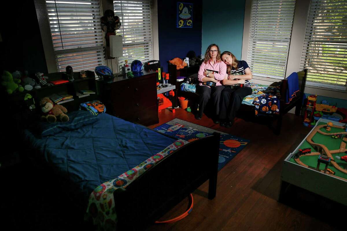 Holding pictures of their two foster kids, parents Angela Sugarek, left, and Carol Jeffery sit on the bed of the younger of their two foster children Wednesday, April 27, 2016 in Houston. The couple had the two bothers, ages three and four, taken away from them by Child Protective Services after reporting that they believed the younger child was being abused by an older brother. ( Michael Ciaglo / Houston Chronicle )