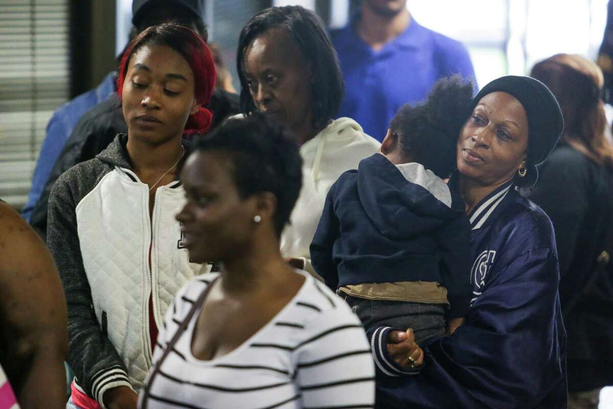 Kiesha James, left, waits in a line with her mother, Shelly Russell, right, and her son, Brandon Beck, 2, for one of four FEMA disaster recovery centers to open Monday in Houston. Officials stressed that residents should register for aid even if they think they don't qualify.