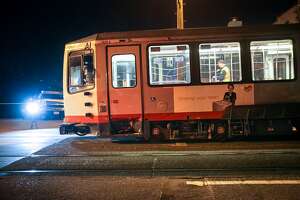 SFMTA officials investigate an L-Taraval Muni train which was hit by a car at the corner of 14th Avenue and Ulloa Street, Friday, Jan. 23, 2015, in San Francisco, Calif.