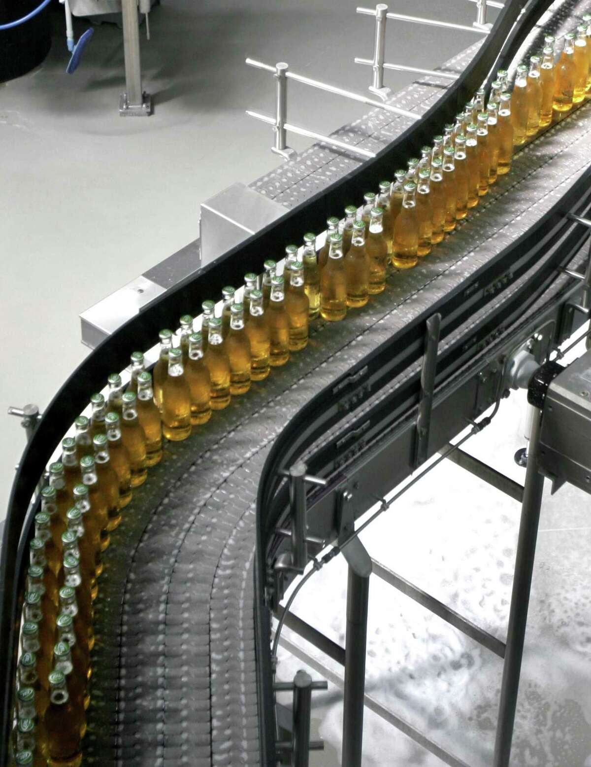 Bottles of beer move down a conveyor at the Anheuser-Busch brewery in St. Louis. It announced it would get 100 percent of its electricity from renewable sources by 2025 on Tuesday, the same day that President Donald Trump signed his executive order.