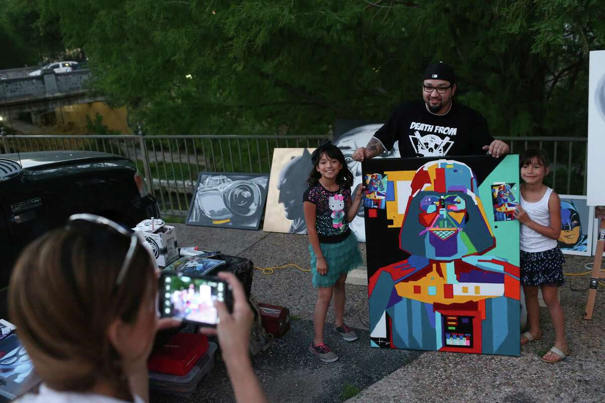 Arlene Cavazos photographs her daughters, Sunshine Vega, 9, left, and Sky Vega, 8, with artist Adrian De La Cruz and his painting of Darth Vader as fans of “Star Wars” fans gather at The Korova to celebrate May the 4th Be With You, Wednesday, May 4, 2016. Fans took on the popular quote in the “Star Wars,” movies, May the Force be with you as a reason to celebrate May 4.
