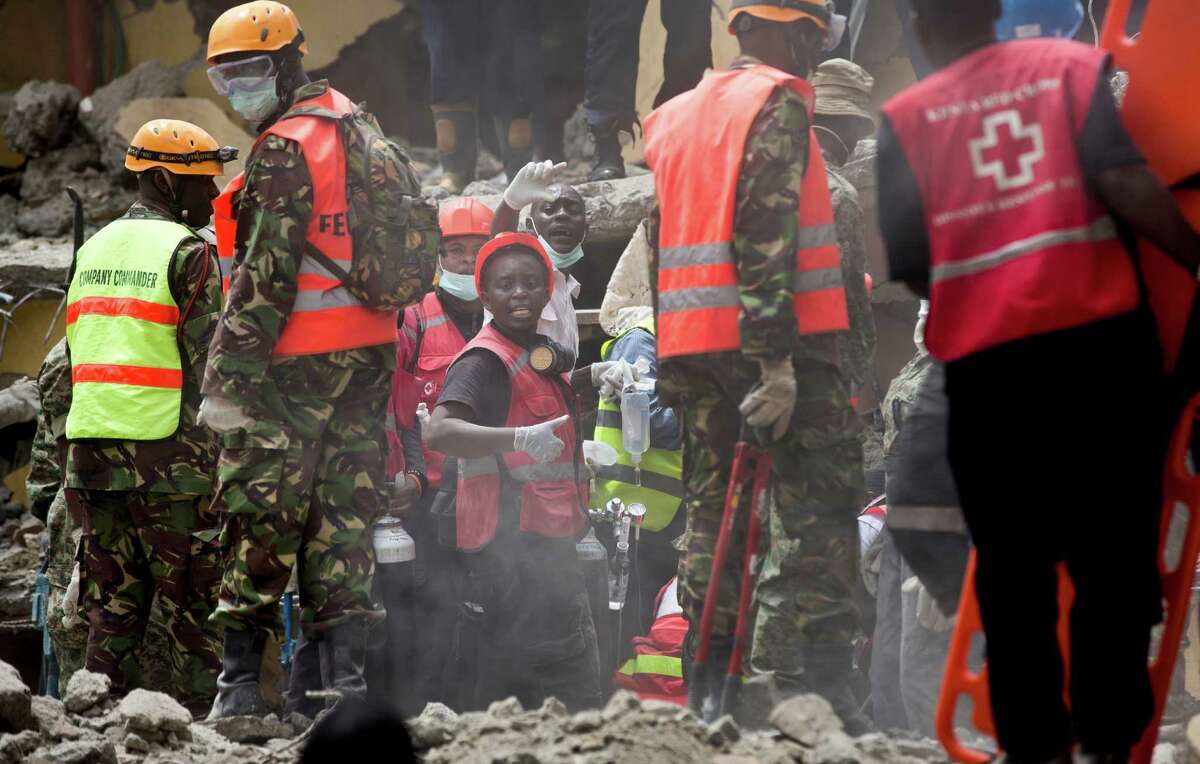 Rescuers gesture to their colleagues as they try to free a woman who was trapped for six days in the rubble of a collapsed building, in the Huruma area of Nairobi, Kenya Thursday, May 5, 2016. After discovering the woman alive and conscious, rescuers administered an IV and oxygen but then had to work for a number of hours to free her from the rubble she was trapped in, before taking her away to hospital. (AP Photo/Ben Curtis)