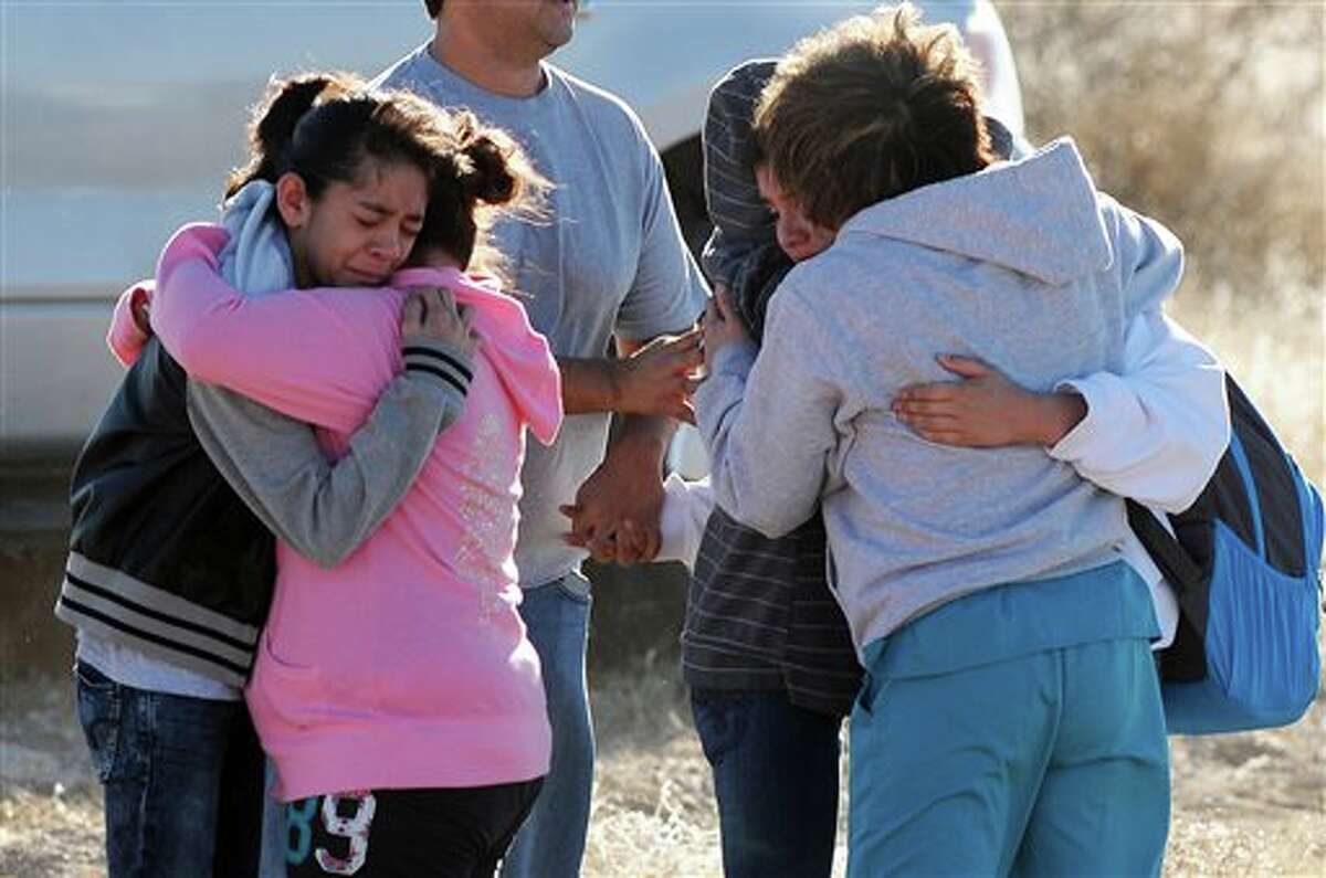 Students are reunited with family following a shooting at Berrendo Middle School, Tuesday, Jan. 14, 2014, in Roswell, N.M. Roswell police said the suspected shooter was arrested at the school, but authorities have not said if there were any injuries. The school has been placed on lockdown. No other details are yet available. (AP Photo/Roswell Daily Record, Mark Wilson)
