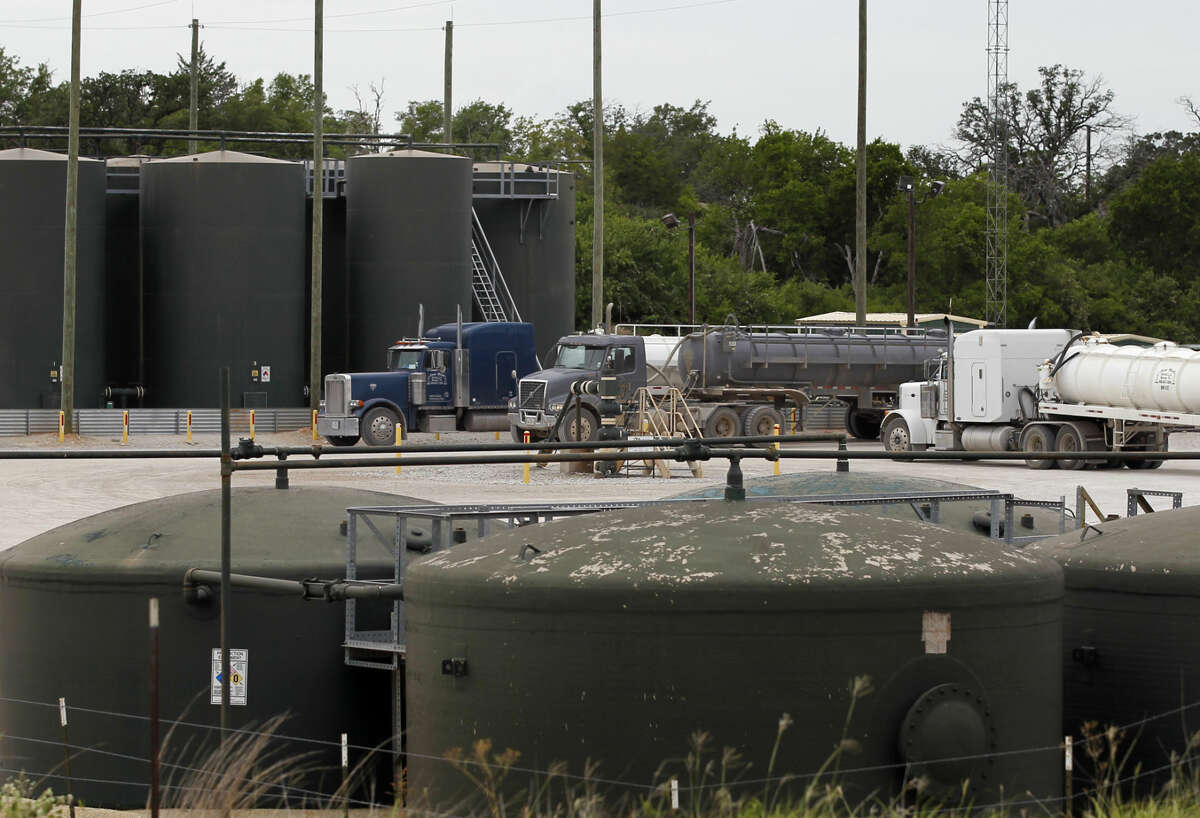 Tractor trailer trucks line up at an XTO Energy Inc. well site waiting to dump their fluid contents into a holding tank, Saturday, June 21, 2014, in Azle, Texas. Earthquakes used to be unheard of on the vast stretches of prairie that unroll across Texas and Oklahoma. But in recent years, temblors have become commonplace. (AP Photo/Tony Gutierrez)