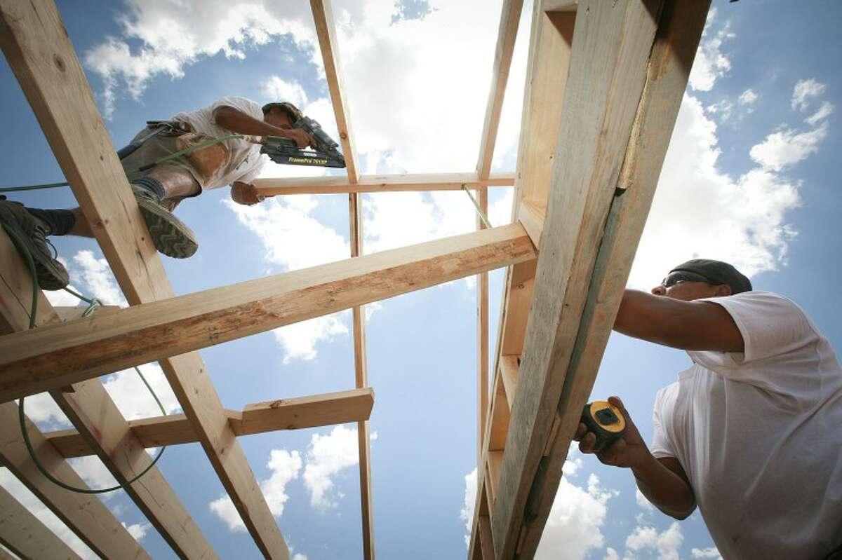 (File Photo) Rafael Rodriguez, left, nails a rafter to a ridge board as Joe Ramirez Jr. measures the roofs rise Friday at a new home construction site located on the 1400 block of E. Jax Ave. Cindeka Nealy/Reporter-Telegram