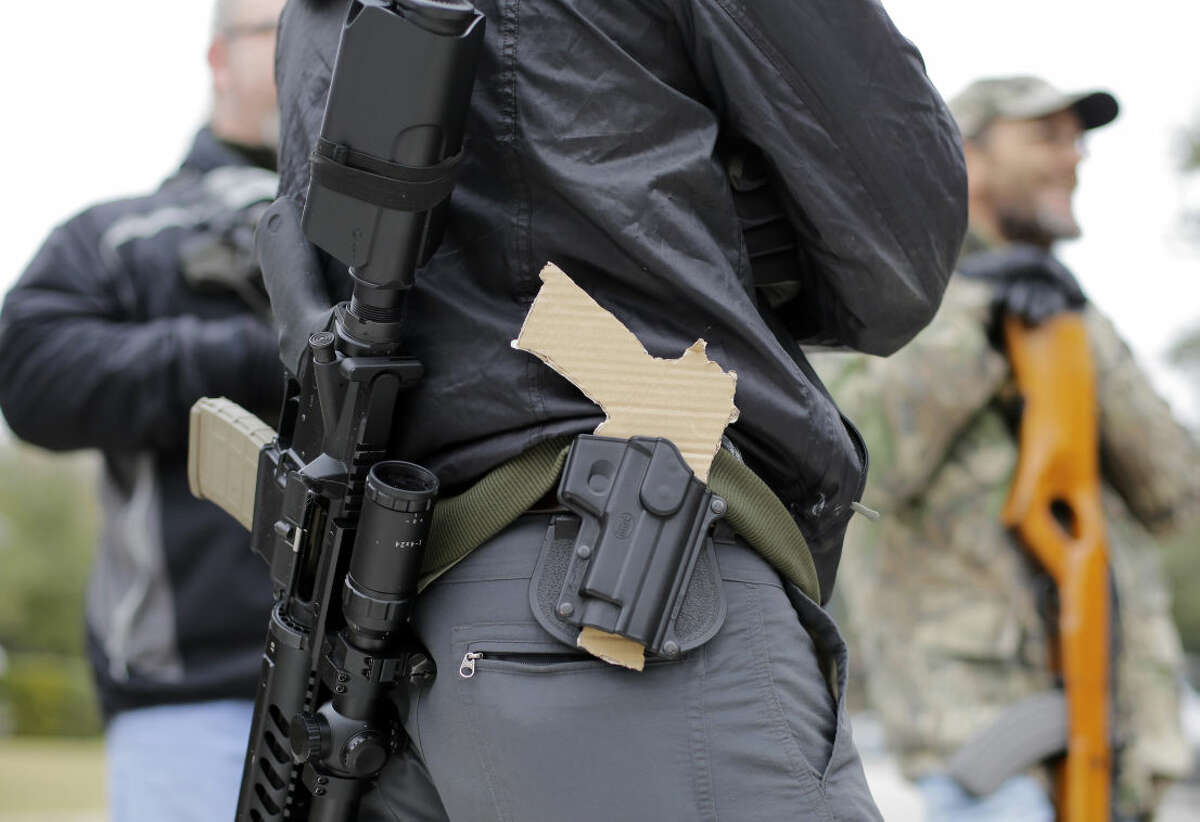 FILE - In this Jan. 13, 2015, file photo, a gun-rights advocate carries a rifle on his back and a cardboard cutout of a pistol on his waist as a group protests outside the Texas Capitol, in Austin, Texas. Texas lawmakers on Friday, May 29, 2015, approved carrying handguns openly on the streets of the nation's second most-populous state, sending the bill to Republican Gov. Greg Abbott, who is expected to sign it and reverse a ban dating to the post-Civil War era. (AP Photo/Eric Gay, File)