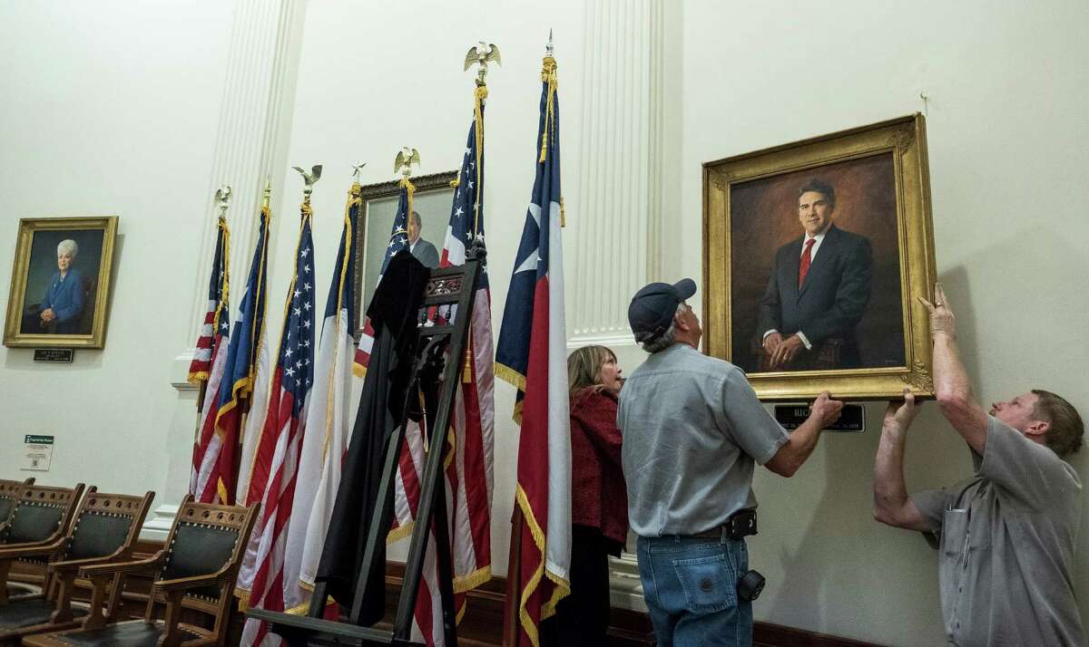 State Preservation Board staff members, Ali James, Rick Grimes, and Bill Klinebecker, left to right, hang the portrait of former Governor Rick Perry following Perry's portrait installation ceremony held at the State Capitol rotunda in Austin, Texas, on Friday, May 6, 2016. RODOLFO GONZALEZ / AUSTIN AMERICAN-STATESMAN