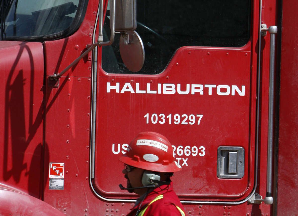 An unidentified worker passes a truck owned by Halliburton at a remote site for natural-gas producer Williams in Rulison, Colo. Halliburton is buying rival oilfield services company Baker Hughes in a cash-and-stock deal worth $34.6 billion, according to reports.