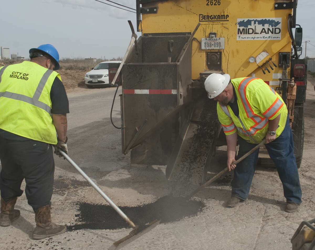 David Vasquez and Abe Langston, white hat, with City of Midland Transportation, fill a pothole with hot asphalt Thursday, 1-29-15, at the intersection of Cotton Flat and Francis. Tim Fischer\Reporter-Telegram