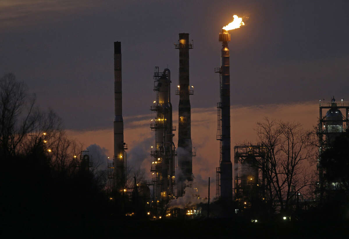 FILE - In this Feb. 13, 2015 file photo, stacks and burn-off from the Exxon Mobil refinery are seen at dusk in St. Bernard Parish, La. The price of U.S. crude oil on Tuesday, Aug. 11, 2015 tumbled to its lowest level in more than six years. (AP Photo/Gerald Herbert, File)